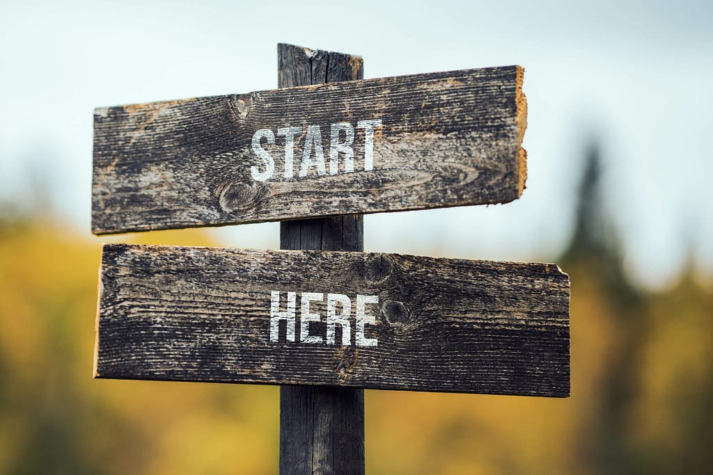 Houten wegwijzer met de tekst 'Start here'